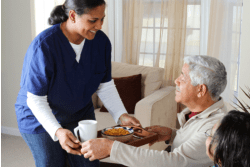 A nurse is serving food to an elderly man.